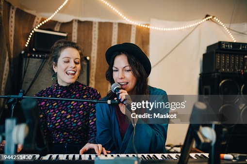 Performers playing piano and singing while practicing in studio Performers playing piano and singing while practicing in studio