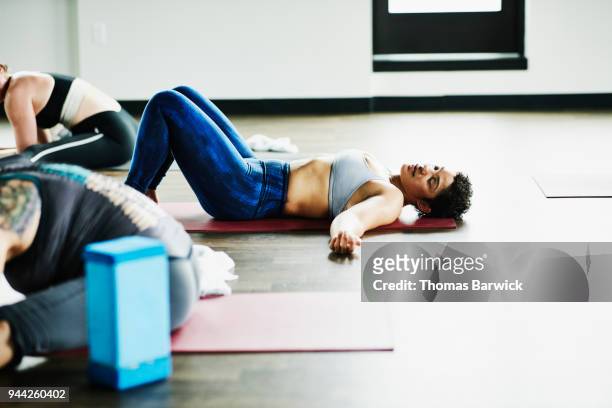 Sweating woman lying on yoga mat after hot yoga class in fitness studio