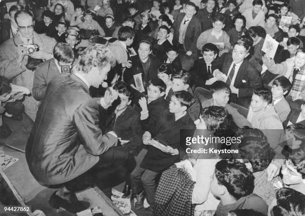 French singer and actor Johnny Hallyday signs autographs for young fans after performing at the world premiere of Jean-Paul Le Chanois's film...