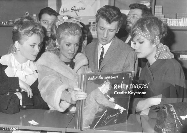 French singer and actor Johnny Hallyday and actress Catherine Deneuve find a copy of Hallyday's record 'Salut les Copains' at a record shop in Paris,...