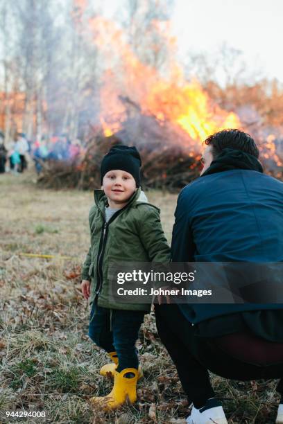 father with son looking at fire in park - walpurgisnacht stock-fotos und bilder