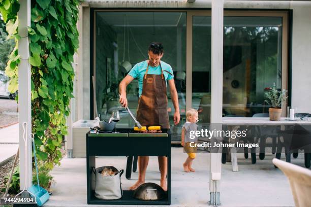 man barbecuing in garden - apron man stock pictures, royalty-free photos & images