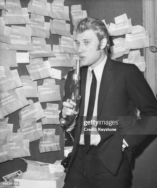 French singer and actor Johnny Hallyday in his dressing room at the Paris Olympia, with a pistol and a number of telegrams sent by admirers, 26th...
