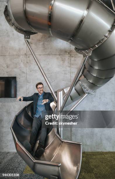 jonge gelukkig ondernemer plezier terwijl glijden in het kantoor. - slide stockfoto's en -beelden