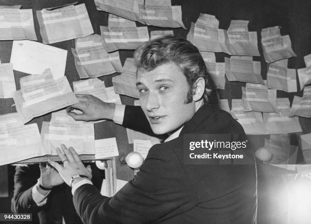 French singer and actor Johnny Hallyday in his dressing room at the Paris Olympia, with a number of telegrams sent by admirers, 26th November 1965.