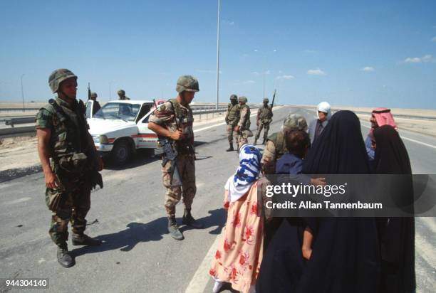 At a checkpoint, American soldiers talk with a group of refugees during the Gulf War, Iraq, 1991.