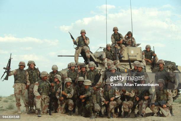 Group portrait of American soldiers as they pose around a Bradley Fighting Vehicle, nicknamed 'Hellrazor,' during the Gulf War, Iraq, 1991.