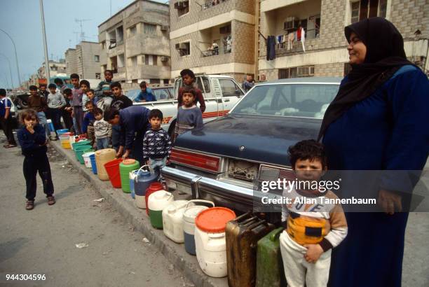 View of a line of Palestinians as they wait, with plastic buckets and cans, for water distribution during the Gulf War, Kuwait City, Kuwait, 1991.