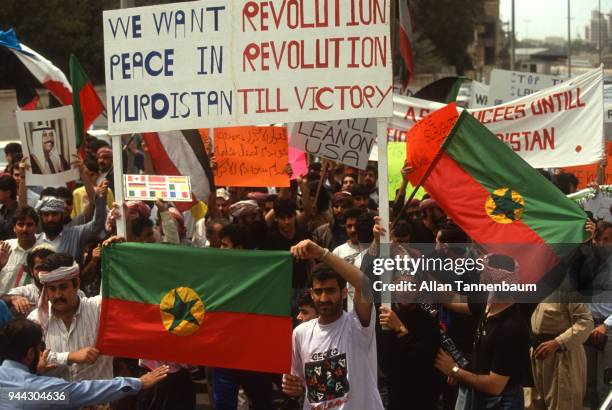 View of protestors, many with signs and flags, as they march during a peace demonstration during the Gulf War, Iraq, 1991. Among the visible signs is...