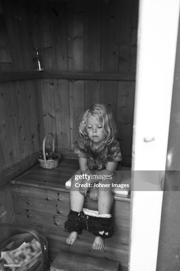 Girl sitting in outhouse