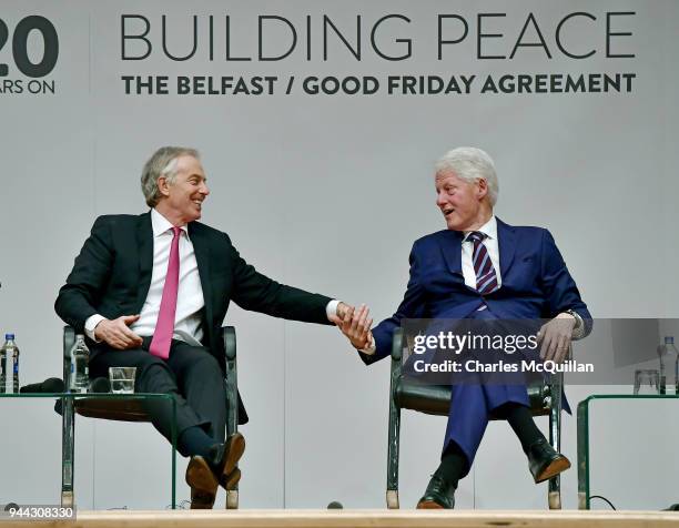 Former US President Bill Clinton holds hands with former British Prime Minister Tony Blair as they attend an event to mark the 20th anniversary of...