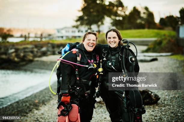 laughing female dive partners standing together on beach after open water dive - dive adventure foto e immagini stock