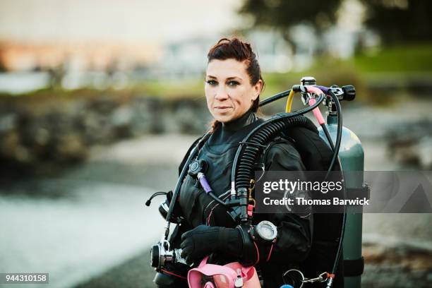 smiling female diver standing on beach after open water dive - dive adventure foto e immagini stock