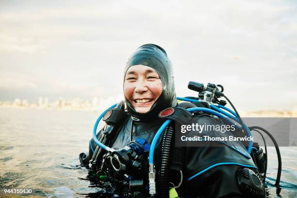 portrait of smiling female diver standing in water before open water dive - dykarutrustning bildbanksfoton och bilder
