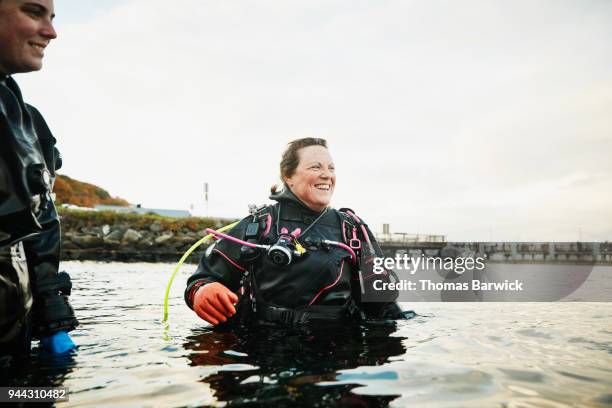 smiling female diver in discussion with friends while standing in water after open water dive - dive adventure foto e immagini stock