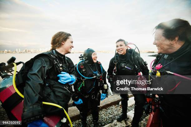 smiling and laughing female divers in discussion on shoreline after open water dive - dive adventure foto e immagini stock