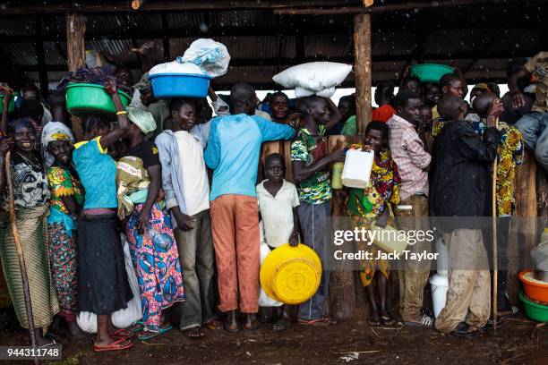 Refugees from the Democratic Republic of Congo stand under a shelter with their food collected from the World Food Programme as it rains in the...