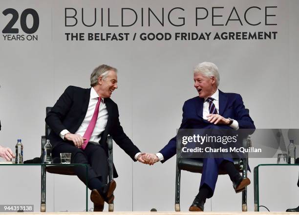 Former US President Bill Clinton holds hands with former British Prime Minister Tony Blair as they attend an event to mark the 20th anniversary of...