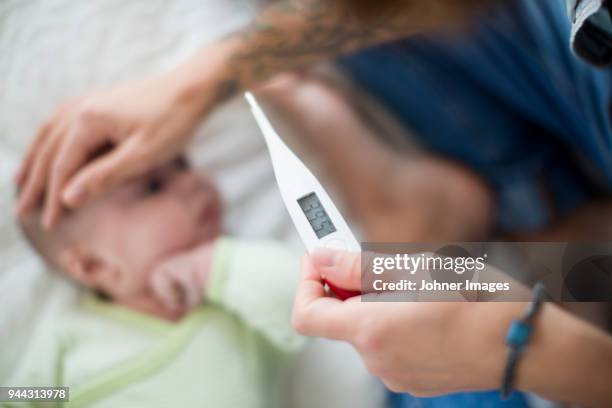 mother checking babys temperature - fever stock pictures, royalty-free photos & images