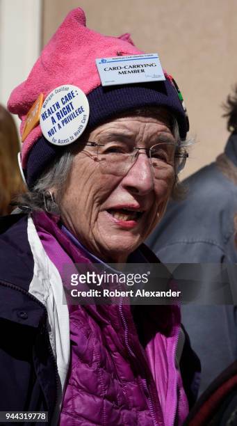 Woman wearing a pink 'pussy hat' adorned with buttons supporting the American Civil Liberties Union, universal health care and other Progressive...