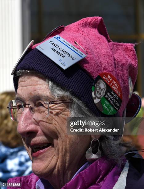 Woman wearing a pink 'pussy hat' adorned with buttons supporting the American Civil Liberties Union, universal health care and other Progressive...