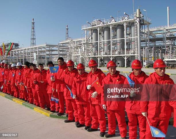 Workers hold flags before the opening ceremony at a refinery in Samandepe on December 14, 2009. China's President Hu Jintao on Monday unveiled a...