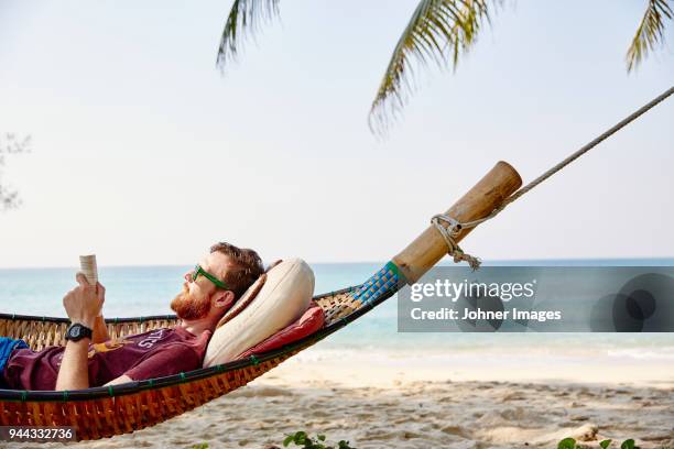 man on hammock reading - strand liegen stock-fotos und bilder