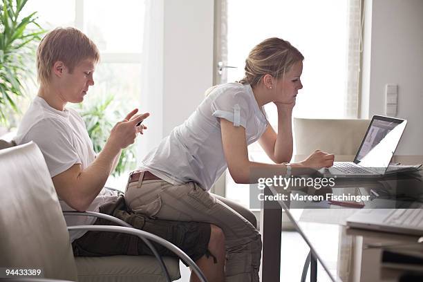 girl sitting on boy's lap working at a computer - mareen fischinger stock-fotos und bilder