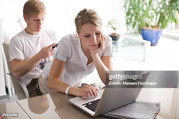 girl sitting on boy's lap working on a computer - mareen fischinger stock pictures, royalty-free photos & images