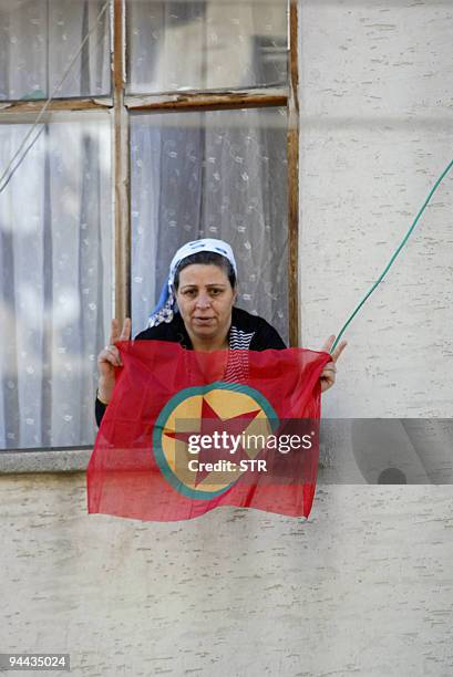 Kurdish woman waves a PKK flag from her house during a clash between Kurds and Turkish police in Diyarbakir on December 14, 2009. Riot police used...