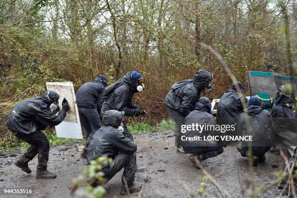 Protesters shelter as clashes erupt during a police operation to raze the decade-old camp known as ZAD at Notre-Dame-des-Landes, near the western...