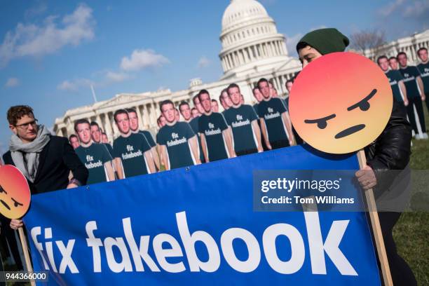 Chelsea Hornick-Becker and Joseph Huff-Hannon set up a display of Facebook CEO Mark Zuckerberg cutouts on the east lawn of the Capitol ahead of his...