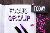 Handwriting text Focus Group. Concept meaning Interactive Concentrating Planning Conference Survey Focused written on Notebook Book on wooden background Today with Thumb Pin Marker Paper Clip.