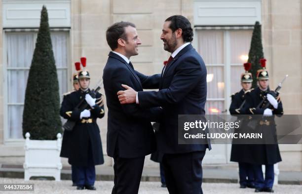 French President Emmanuel Macron greets Lebanese Prime Minister Saad Hariri as he arrives for an official dinner at The Elysee Palace in Paris on...