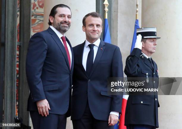 French President Emmanuel Macron greets Lebanese Prime Minister Saad Hariri as he arrives for an official dinner at The Elysee Palace in Paris on...