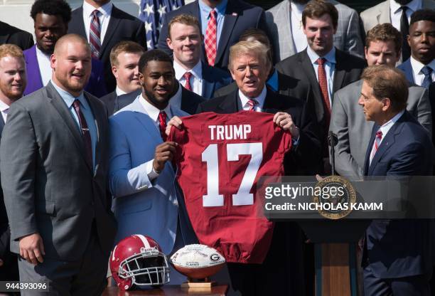 President Donald Trump receives a jersey from the 2017 NCAA football national champions the Alabama Crimson Tide's Bradley Bozeman and Rashaan Evans...