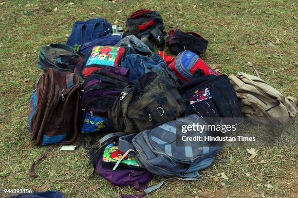 School bags and a stuffed toy are seen near the mangled remains of a school bus after it fell into a gorge near Gurchal village, near Nurpur on April...