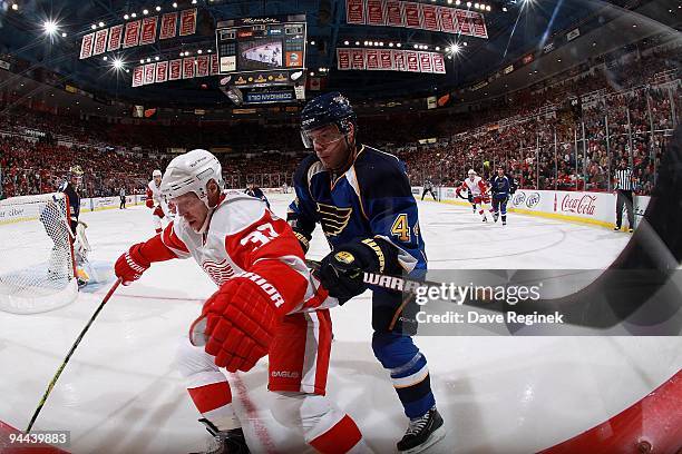 Kris Draper of the Detroit Red Wings protects the puck from Darryl Sydor of the St. Louis Blues during a NHL game at Joe Louis Arena on December 9,...