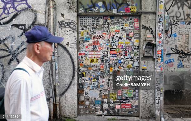 This picture taken on March 30, 2018 shows a man walking past a door pasted with various stickers in Taipei's Ximen district. / AFP PHOTO / SAM YEH