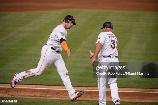 Justin Bour of the Miami Marlins slaps hands with third base coach Fredi Gonzalez after hitting a two run home run during the fifth inning of the...