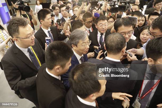 Yi Gang, governor of the People's Bank of China , center, is surrounded by members of the media as he departs following a panel discussion at the...