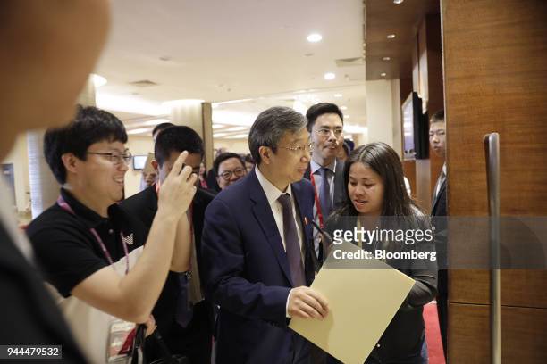 Yi Gang, governor of the People's Bank of China , center, arrives for a panel discussion at the Boao Forum for Asia Annual Conference in Boao, China,...