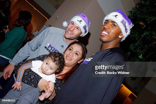 Jason Thompson and Jon Brockman of the Sacramento Kings pose for a photo with a family on December 13, 2009 at Shriners Hospital for Children in...
