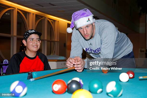 Jon Brockman of the Sacramento Kings gets ready to play pool with a young fan on December 13, 2009 at Shriners Hospital for Children in Sacramento,...