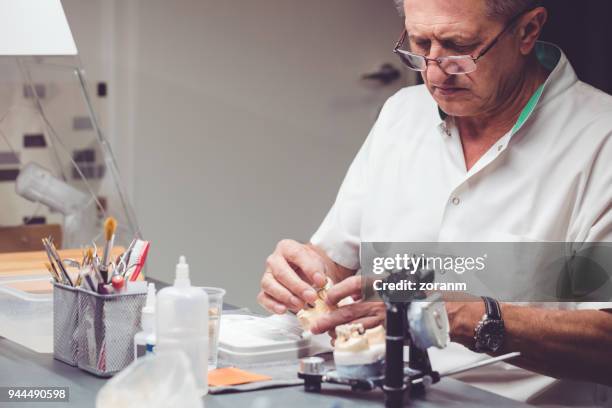 senior technician processes the artificial teeth - acrylic fiber stock pictures, royalty-free photos & images