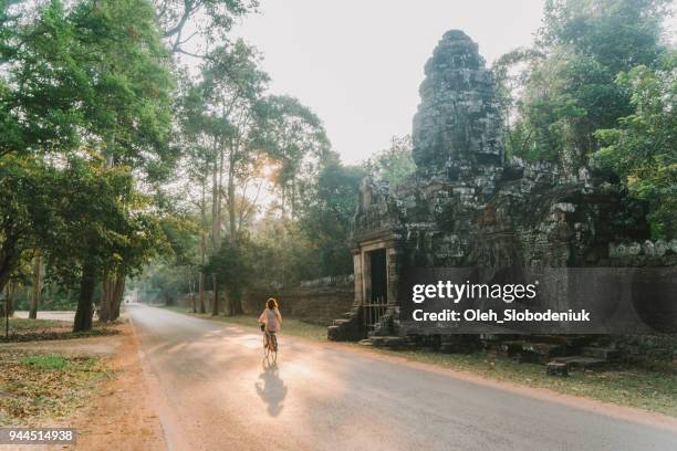 junge kaukasischen frau reiten fahrrad in angkor wat - angkor wat stock-fotos und bilder