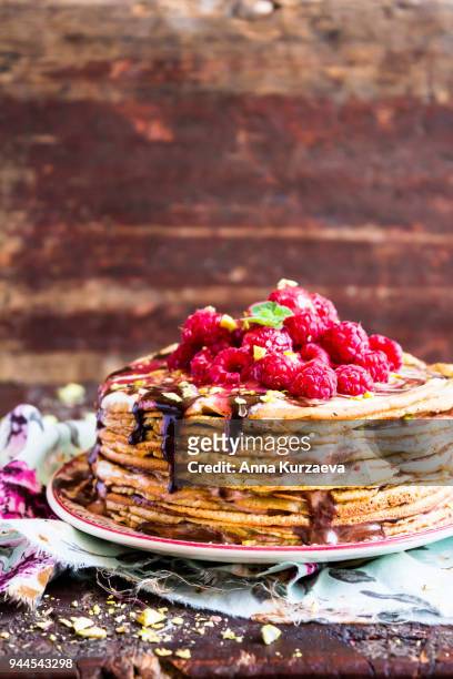 stack of wheat golden pancakes or pancake cake with freshly picked raspberry, chopped pistachios, chocolate sauce on a dessert plate, selective focus - week 2012 celebration stock pictures, royalty-free photos & images