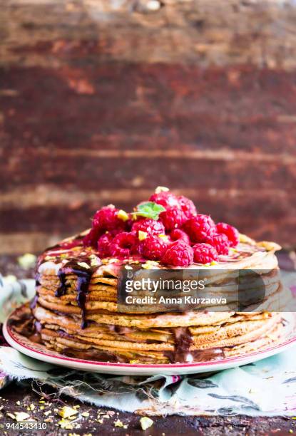 stack of wheat golden pancakes or pancake cake with freshly picked raspberry, chopped pistachios, chocolate sauce on a dessert plate, selective focus - week 2012 celebration stock pictures, royalty-free photos & images