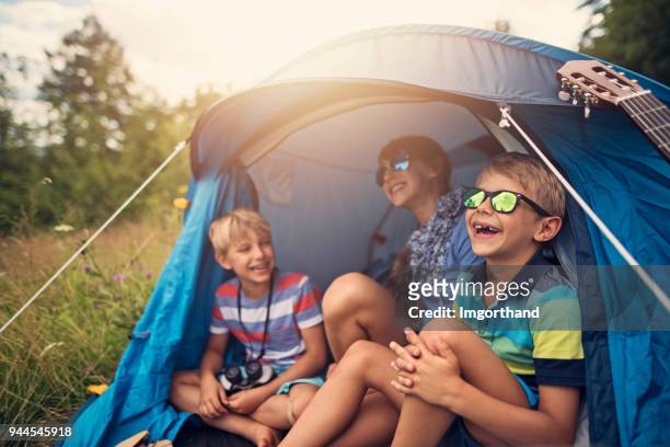 los niños que se divierten acampar en carpa en el prado del bosque - acampar fotografías e imágenes de stock