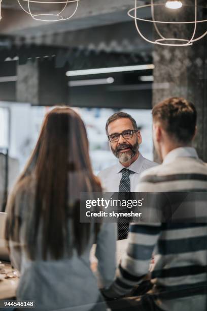 happy mature insurance agent talking to a couple in the office. - happy customer stock pictures, royalty-free photos & images